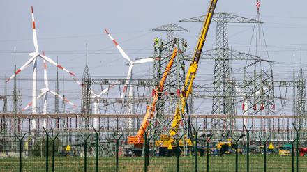 Monteure errichten einen Strommast in der Nähe von Windkraftanlagen in Sachsen-Anhalt. 