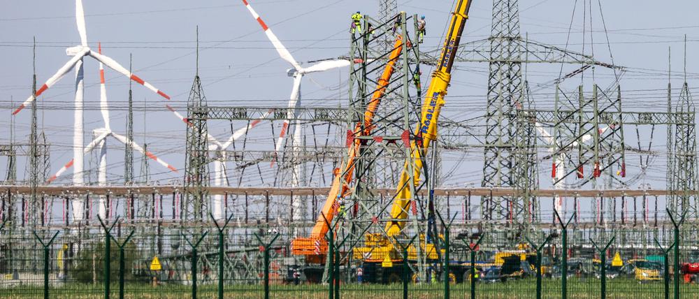 Monteure errichten einen Strommast in der Nähe von Windkraftanlagen in Sachsen-Anhalt.