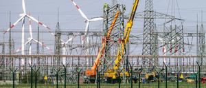 Monteure errichten einen Strommast in der Nähe von Windkraftanlagen in Sachsen-Anhalt. 