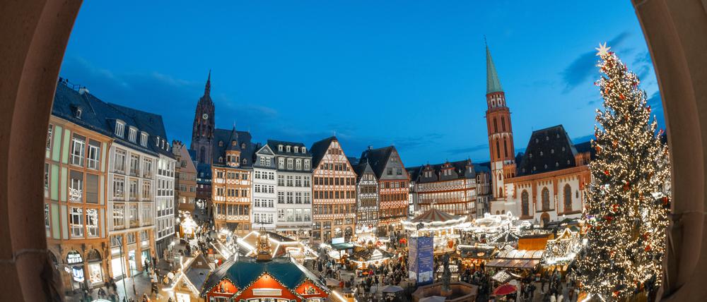ARCHIV - 26.11.2024, Hessen, Frankfurt/Main: Die Lichter von Verkaufsbuden und Fahrgeschäften leuchten neben dem Weihnachtsbaum «Florian» auf dem traditionellen Weihnachtsmarkt auf dem Römerberg in Frankfurt.