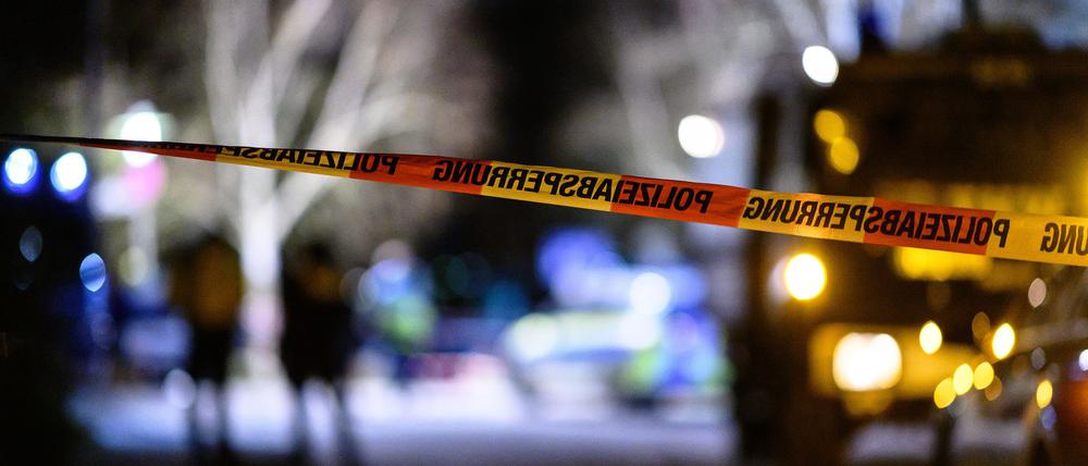 Ein Flatterband der Polizei ist vor Einsatzfahrzeugen am Tatort zu sehen.