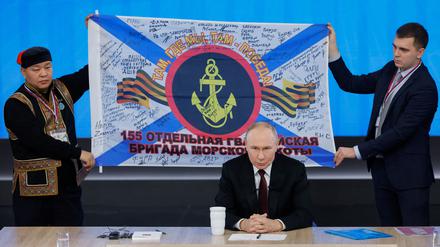 Putin präsentiert während der Pressekonferenz Geschenke von russischen Soldaten, hier eine unterschriebene Flagge von Angehörigen der Pazifikflotte.