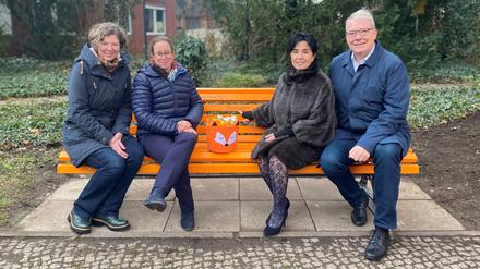 Stadträtinnen Korinna Stephan (Grüne), Julia Schrod-Thiel, Bürgermeisterin Emine Demirbüken-Wegner, Stadtrat Harald Muschner (alle drei CDU, von links nach rechts) auf einer orangefarbenen Bank, die gegen Gewalt an Frauen und Mädchen sensibilisieren soll.