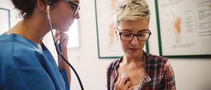 Eine Ärztin (links) untersucht den Oberkörper einer Patientin mit einem Stethoskop.