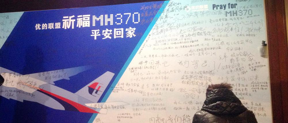 Das Foto zeigt eine Frau vor einer Wand mit Gebetsbekundungen und Nachrichten von Angehörigen der vermissten Passagiere des Malaysia Airlines-Flugs MH370. Es wurde am 20. März 2014 aufgenommen.