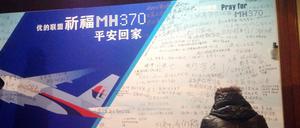 Das Foto zeigt eine Frau vor einer Wand mit Gebetsbekundungen und Nachrichten von Angehörigen der vermissten Passagiere des Malaysia Airlines-Flugs MH370. Es wurde am 20. März 2014 aufgenommen.
