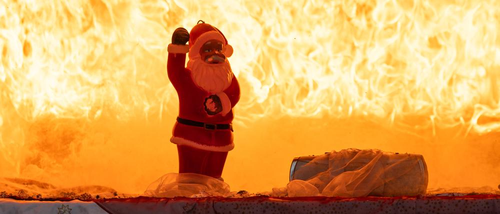 Eine Weihnachtsmannfigur steht vor einem Meer aus Flammen. (Symbolbild)