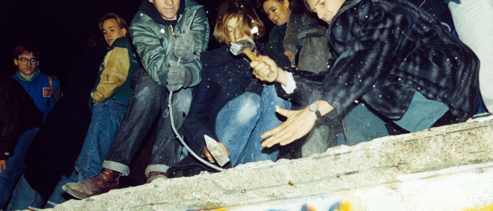 West-Berliner versuchen mit Hämmern und Kreuzhacken die Berliner Mauer einzureißen.