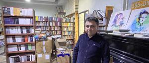 Jehat Rojhilat vor dem verstimmten Klavier im Buchladen, auf dem Porträts bekannter kurdischer Dichter und Sänger stehen.