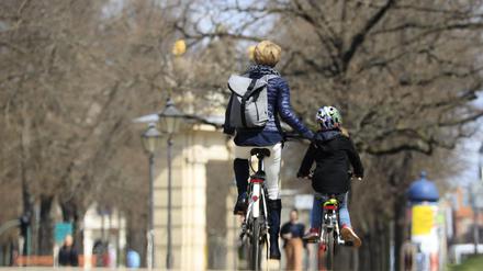 Eine Mutter fährt neben ihrer Tochter Fahrrad.