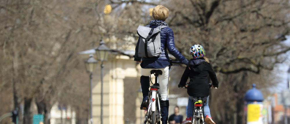 Eine Mutter fährt neben ihrer Tochter Fahrrad.