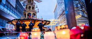 Polizisten sichern den Weihnachtsmarkt in Magdeburg, wobei Kerzen vor ihnen brennen.
