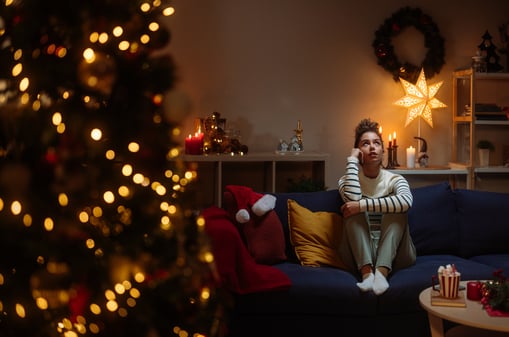Eine Frau sitzt allein neben einem Weihnachtsbaum. (Symbolbild)