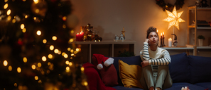 Eine Frau sitzt allein neben einem Weihnachtsbaum. (Symbolbild)