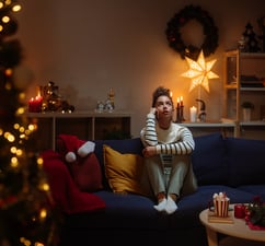 Eine Frau sitzt allein neben einem Weihnachtsbaum. (Symbolbild)