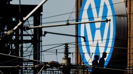 Die Silhouetten von zwei Männern auf einer Brücke zeichnen sich am 10.05.2016 vor dem großen Volkswagen Logo am Kraftwerk am VW Werk in Wolfsburg (Niedersachsen) ab. 