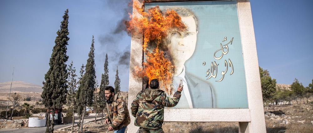 Syrische Rebellen verbrennen ein Bild des gestürzten Machthabers Assad.