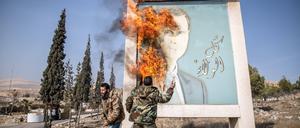 Syrische Rebellen verbrennen ein Bild des gestürzten Machthabers Assad.