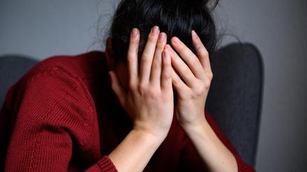 ARCHIV - 18.02.2023, Hamburg: Eine Frau sitzt mit dem Kopf in den Händen auf einem Stuhl. (gestellte Szene)