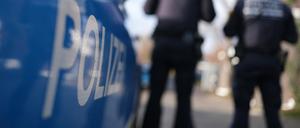 Zwei Polizisten stehen neben einem Dienstfahrzeug.