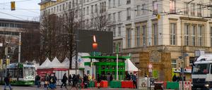 Eine Kerze ist in der Innenstadt auf einer Videoleinwand zu sehen.