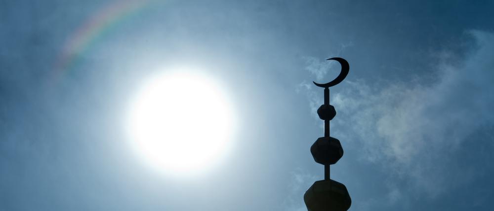 Der Halbmond auf dem Minarett einer Moschee hebt sich als Schattenriss vor der Sonne ab. (Symbolbild)