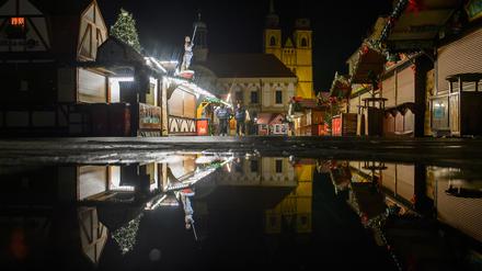 Buden des des Weihnachtsmarktes, das Rathaus und die Johanniskirche spiegeln sich in einer Regenpfütze. Am 20. Dezember 2024 war auf dem Weihnachtsmarkt ein Autofahrer in eine Menschengruppe gefahren. 