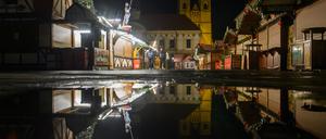 Buden des des Weihnachtsmarktes, das Rathaus und die Johanniskirche spiegeln sich in einer Regenpfütze. Am 20. Dezember 2024 war auf dem Weihnachtsmarkt ein Autofahrer in eine Menschengruppe gefahren. 