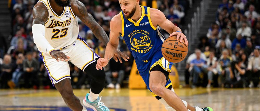 LeBron James (l) und die Los Angeles Lakers setzten sich bei den Golden State Warriors um Stephen Curry durch.