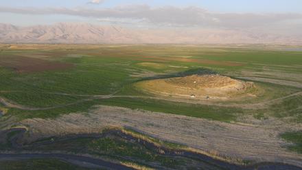 Luftbild des archäologischen Fundortes Gird-i Shamlu im Vordergrund bei laufenden Grabungen. Im Hintergrund das Zagros-Gebirge an der irakisch-iranischen Grenze. 