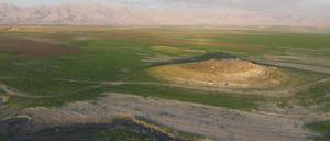 Luftbild des archäologischen Fundortes Gird-i Shamlu im Vordergrund bei laufenden Grabungen. Im Hintergrund das Zagros-Gebirge an der irakisch-iranischen Grenze. 