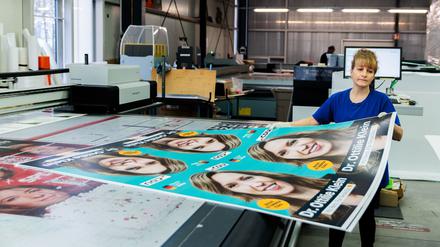 Königs Wusterhausen: Eine Mitarbeiterin bewegt CDU-Plakate an einer Druckmaschine bei Pawellek Siebdruck. 