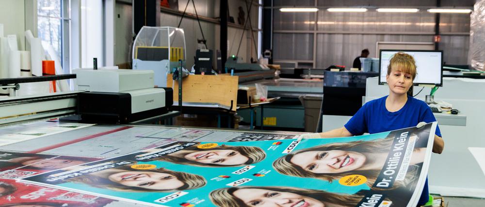 Königs Wusterhausen: Eine Mitarbeiterin bewegt CDU-Plakate an einer Druckmaschine bei Pawellek Siebdruck. 