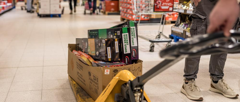 In einem Supermarkt wird ein Karton mit Feuerwerk durch die Regalreihen gefahren. Am heutigen Tag beginnt der Verkauf von Silvesterfeuerwerk. Bis zum Silvestertag werden Böller, Raketen und Feuerwerksbatterien bis zur Kategorie F2 offiziell im Handel angeboten.