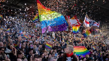 Fans des FC St. Pauli mit Regenbogen-Fahnen und Konfetti  beim Spiel gegen den VfL Wolfsburg.