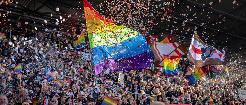 Fans des FC St. Pauli mit Regenbogen-Fahnen und Konfetti  beim Spiel gegen den VfL Wolfsburg.