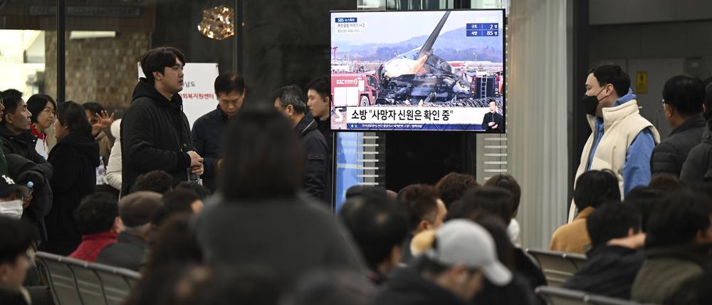 Familienangehörige der Passagiere eines bei der Landung am internationalen Flughafen von Muan in Südkorea verunglückten Passagierflugzeug sehen eine Nachrichtensendung am Flughafen.