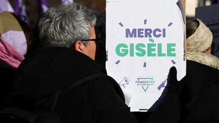 Eine Frau hält ein Schild hoch, auf dem „Danke, Giséle“ steht. 
