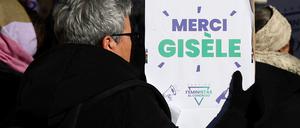 Eine Frau hält ein Schild hoch, auf dem „Danke, Giséle“ steht.