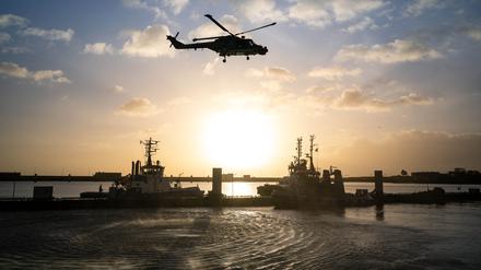 Ein Bundeswehrhubschrauber überfliegt den Marinestützpunkt Wilhelmshaven und die deutsche Fregatte „Hamburg“.