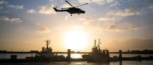 Ein Bundeswehrhubschrauber überfliegt den Marinestützpunkt Wilhelmshaven und die deutsche Fregatte „Hamburg“.