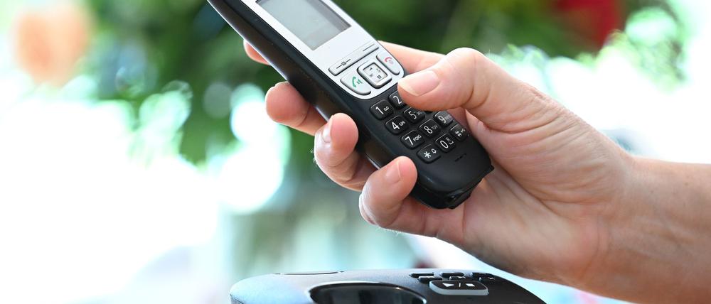 ILLUSTRATION - Eine Frau hölt ein Festnetz-Telefon in ihrer Hand. 