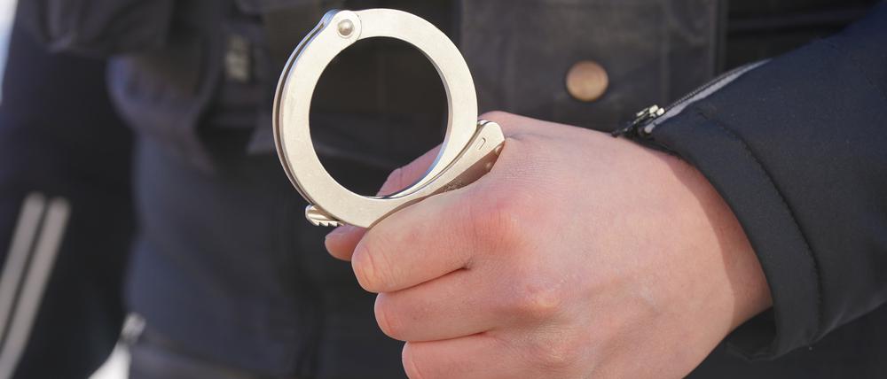 Ein Polizist hält Handschellen in der Hand.
