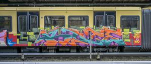 Ein mit Graffiti bemalter S-Bahnzug steht an einem Bahnhof und ist seitlich zu sehen. (Archivbild)
