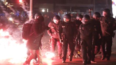 Einsatzkräfte der Polizei stehen in der Silvesternacht zwischen brennendem Feuerwerk in Neukölln. 