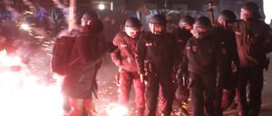 Einsatzkräfte der Polizei stehen in der Silvesternacht zwischen brennendem Feuerwerk in Neukölln. 