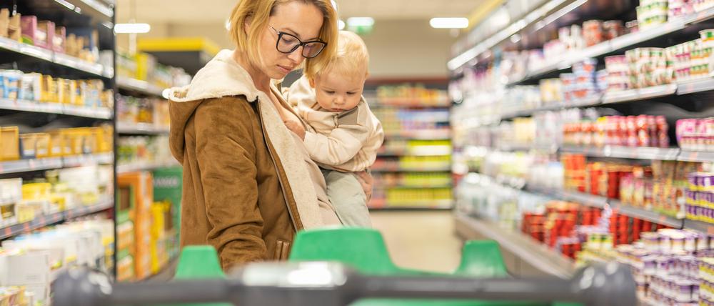 Mutter mit Baby auf dem Arm im Supermarkt.