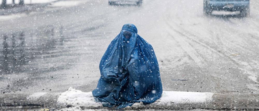 Unsichtbar und zum Schweigen verdammt: eine bettelnde Afghanin auf den verschneiten Straßen von Kabul.