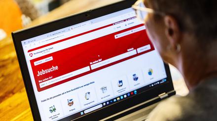 Frau mit Brille auf Jobsuche sitzt zuhause vorm Notebook und informiert sich im Internet auf der Internetseite der Bundesagentur für Arbeit nach Stellenangeboten.