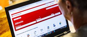 Frau mit Brille auf Jobsuche sitzt zuhause vorm Notebook und informiert sich im Internet auf der Internetseite der Bundesagentur für Arbeit nach Stellenangeboten.